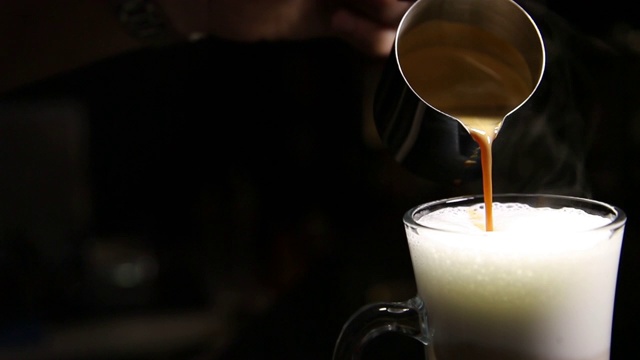 咖啡师用手将咖啡倒入一杯摩卡奇诺或拿铁。模糊的背景。副本的空间。视频素材