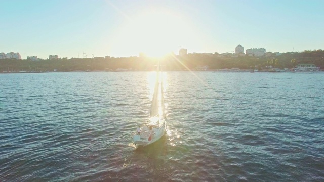 落日余晖下的帆船美景。绿色的海面上有太阳的反光和闪光。无人机视图-鸟瞰角度。视频素材