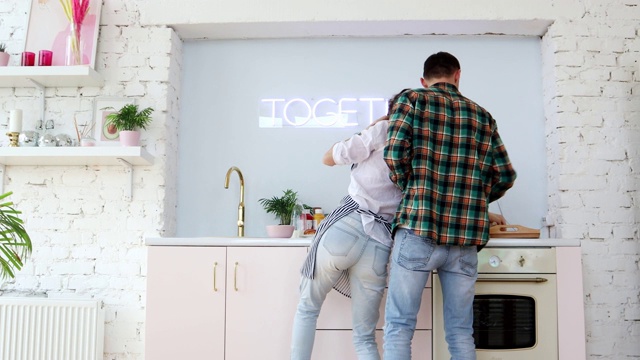 一对欢快的年轻夫妇在厨房边做饭边跳舞。视频素材