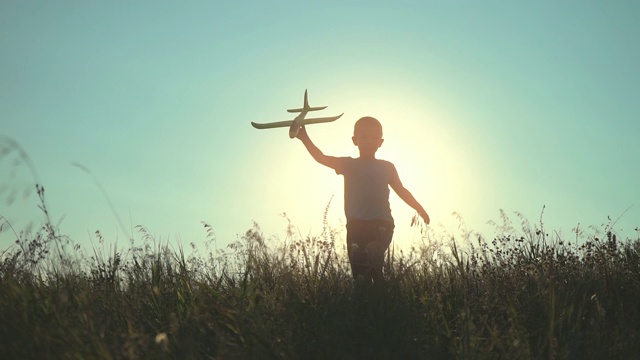 一个男孩手里拿着一架飞机从山上跑下来视频素材
