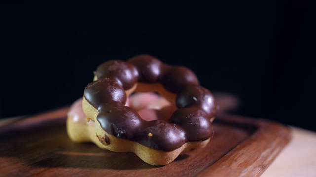 堆叠甜甜圈在木托盘与黑暗的背景，旋转拍摄。视频素材