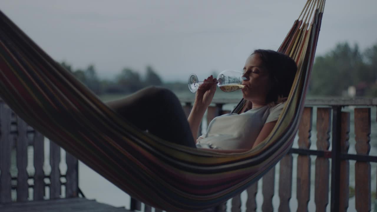 一个女人躺在吊床上喝酒视频素材