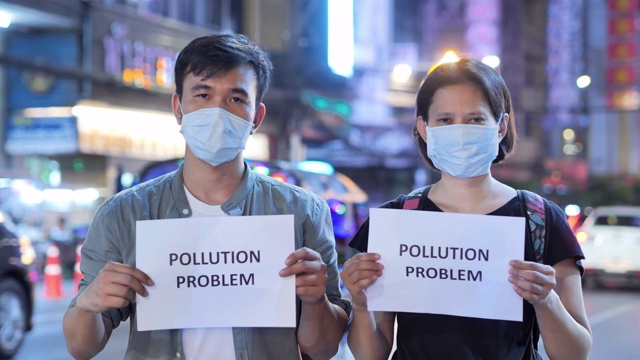 人们戴着防护面具，手持写有“污染问题”的纸卡片。防止吸入有毒空气的面罩。环境污染，生态灾害，人民，交通，工业，能源，社会问题，未来概念。视频素材