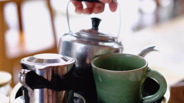 女人的手把红茶从铝茶壶倒到杯子里，视频下载