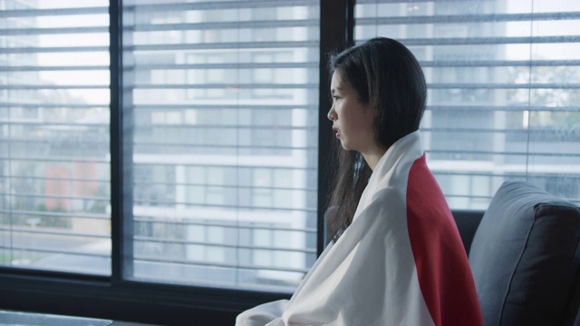 沮丧和悲伤的日本女孩支持者包裹日本国旗在家看电视。红色摄像机拍摄。缓慢的运动。爱国者和体育迷的概念。视频素材