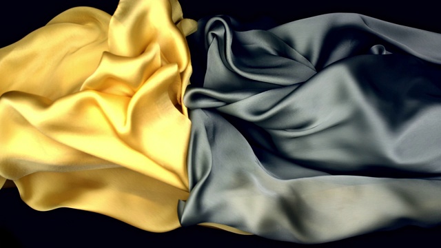 金属银色和金黄色的丝绸面料在超慢的动作中横向流动和摆动，近景，黑色背景视频素材