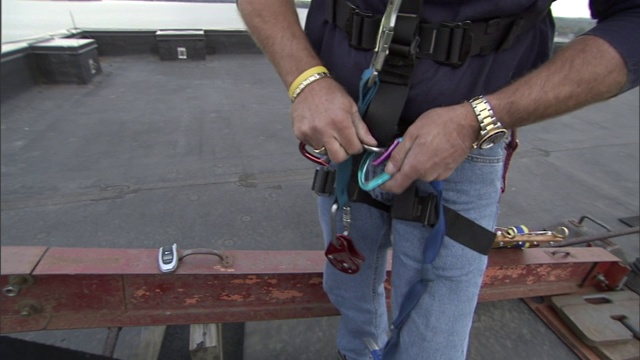 一个男人把安全带和系带系在腰间。视频下载