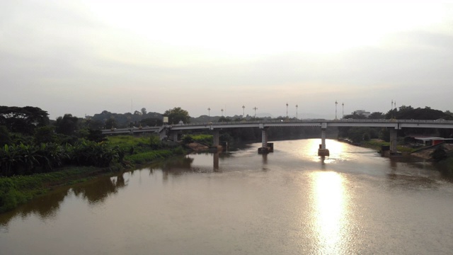 4k日落无人机拍摄，河桥，缓慢提升小车向后渡桥，清莱，泰国，亚洲，城镇。阳光，早晨，东南亚。热带，潮湿，温暖，鸟儿飞过视频素材