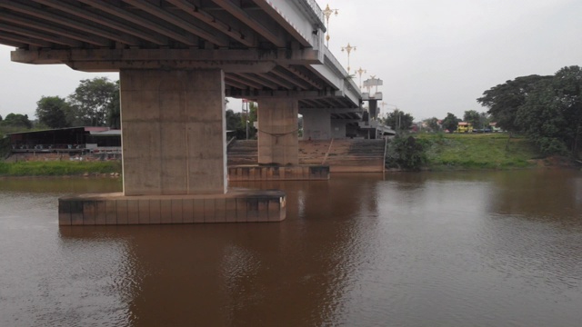 无人机飞过桥下，低角度，桥下渡河，泰国清莱，亚洲，早晨，黎明，黄昏，量度，洪水，东南亚，日落，浑浊的河流视频素材