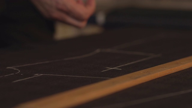 一个裁缝在织物上画线的近距离镜头，用他的粉笔平轮廓做一些裁剪周围的改变视频下载