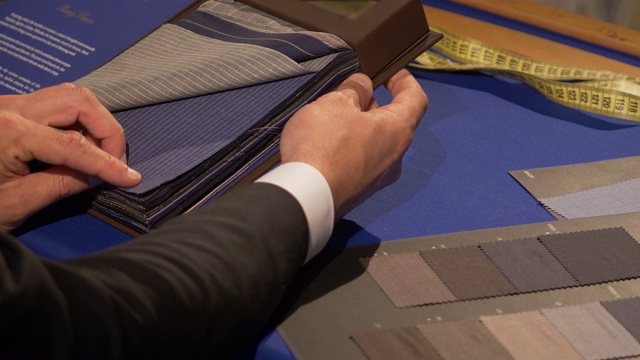 一个裁缝为他的顾客寻找合适衣服的录像视频素材