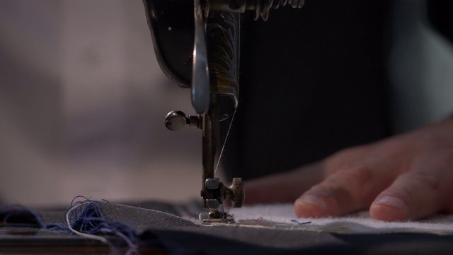 一个裁缝在缝纫机上把两块布缝在一起的低角度镜头视频下载