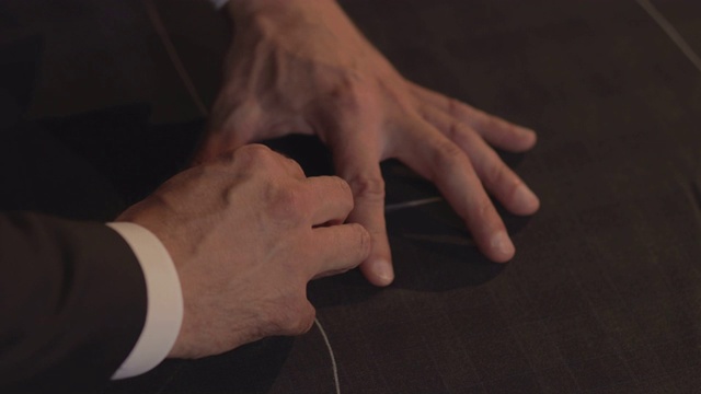 一个裁缝正在用他的粉笔在织物上画线，以便做出一套西装的轮廓视频素材