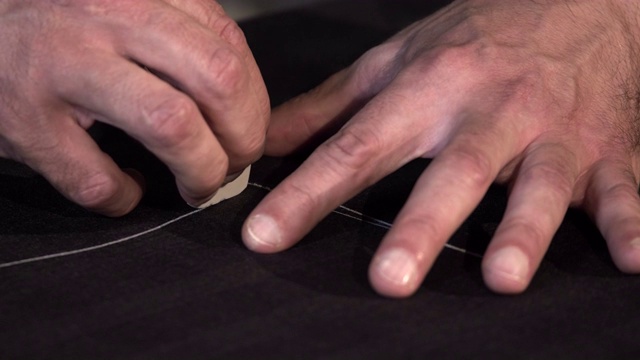一个裁缝在把布料剪成碎片之前在上面做最后的标记视频素材