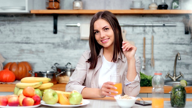 迷人的微笑素食年轻女士喝新鲜橙汁用吸管在家里厨房视频素材