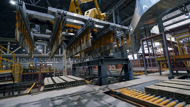 在一个现代化的工厂里，工作臂在生产线上移动砖块。视频素材