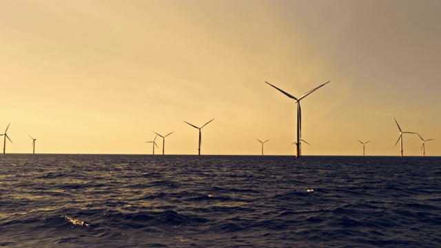 空中风力涡轮机在日落时在海上旋转视频素材