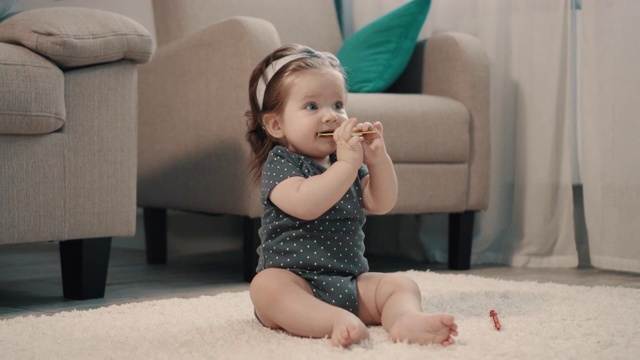 小女孩坐在家里的地板上咬玩具视频素材