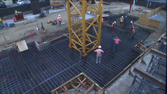 建筑工人通过钢筋网格浇筑水泥。视频素材