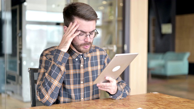 悲伤的年轻设计师在办公室平板电脑上的损失视频素材