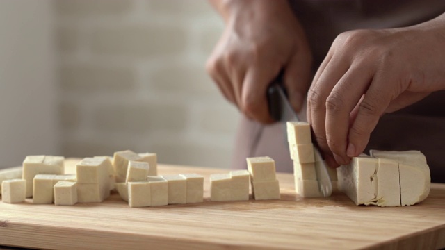 厨师用刀将豆腐切成小块，放在砧板上准备烹饪视频下载