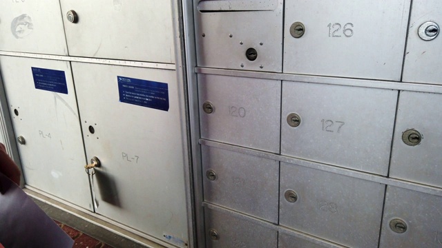 慢镜头中，一名白人男子在社区公寓的邮局里从信箱里取信。视频素材