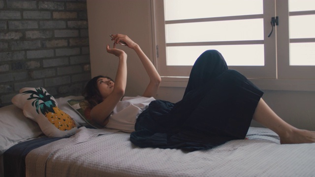日本东京，一名女子躺在床上用手机打字。视频素材