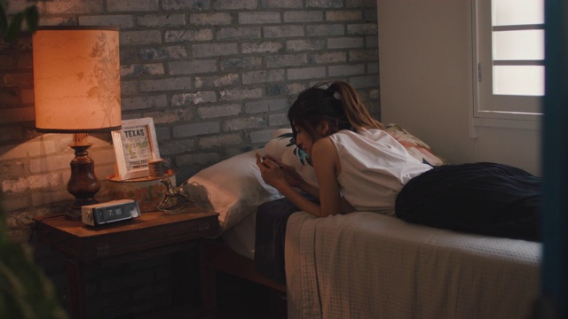 日本东京，一名女子躺在床上用手机打字。视频素材