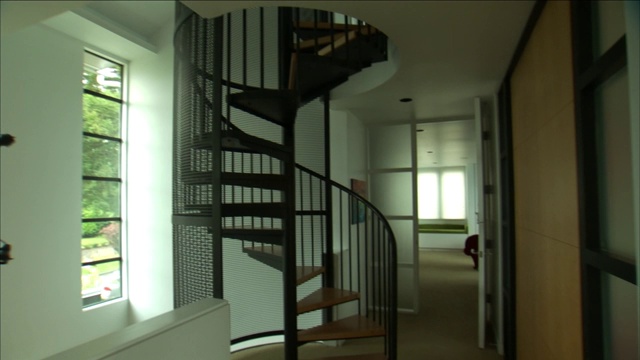 螺旋楼梯通向二楼，旁边是一间现代卧室。视频下载
