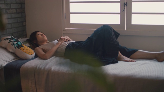 在日本东京，一个女人躺在床上拿着手机。视频素材