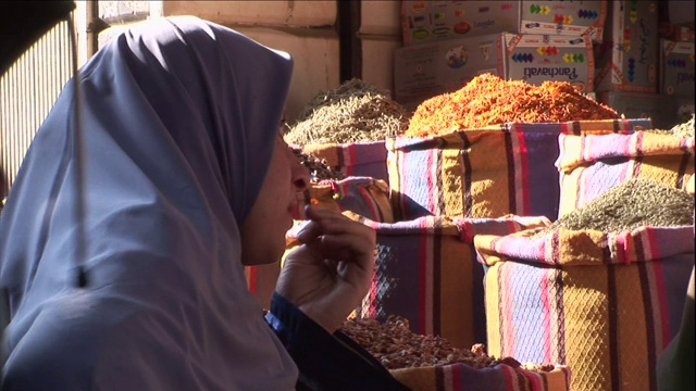 行人走过时，一位妇女看着一袋袋的农产品。视频素材