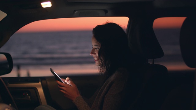 一个年轻女子黄昏时分在车里发短信视频素材