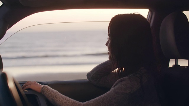 一个年轻女人坐在海边的车里视频素材