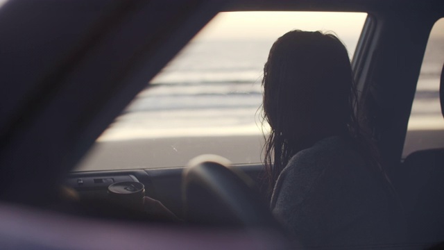 一个年轻女人坐在海边的车里视频下载