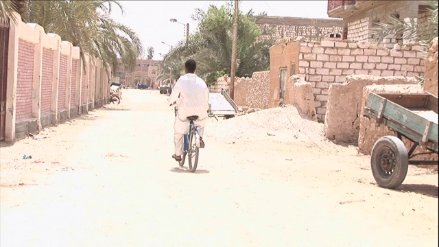 一个骑自行车的人骑在一条土路上。视频下载
