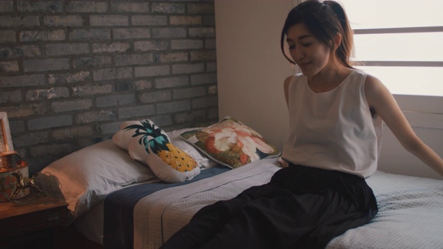 日本东京，一个女人坐在床上用手机打字。视频素材