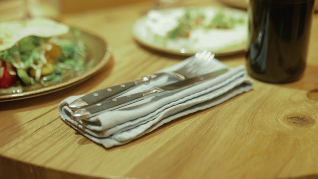 美丽的表设置。在餐馆里，刀叉放在盘子里的餐巾纸上。特写镜头。视频素材