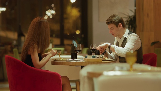 浪漫的咖啡馆约会，一男一女在晚餐时聊天。恩爱夫妻在舒适的咖啡馆里吃喝。侧视图。视频下载