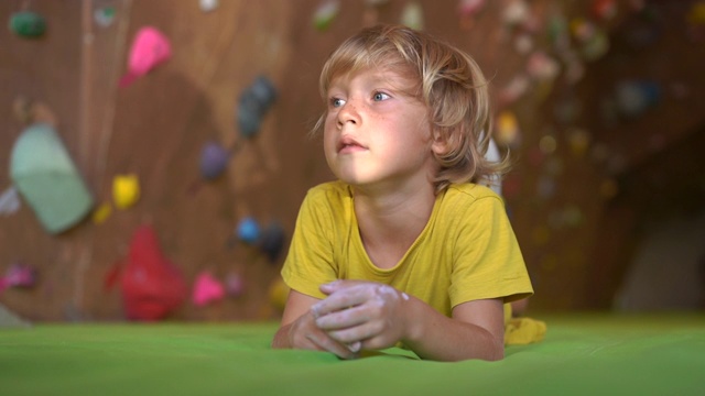一个小男孩正在攀岩馆里爬墙的慢动作镜头视频素材