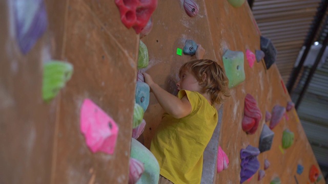 一个小男孩正在攀岩馆里爬墙的慢动作镜头视频素材