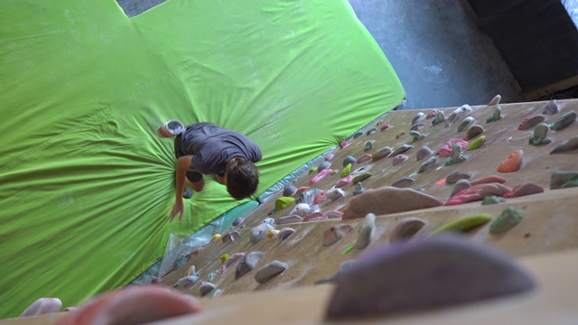 一个年轻人正在攀岩馆里攀岩视频素材
