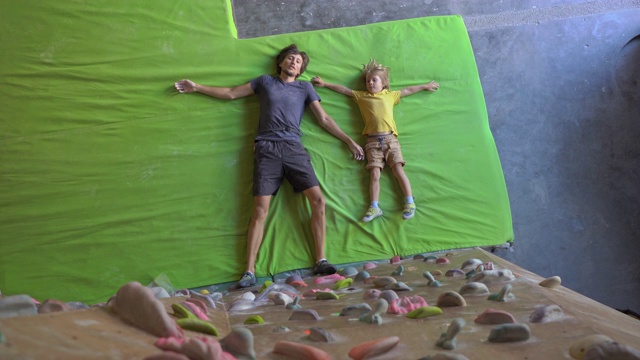 一个年轻的攀岩教练在攀岩馆里教小男孩如何爬墙视频素材