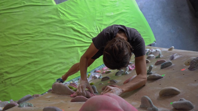 一个年轻人正在攀岩馆里攀岩视频素材