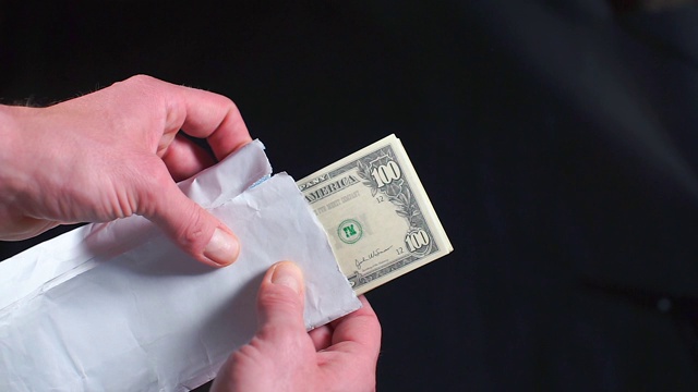一个白色信封里的一捆钱的特写。视频素材