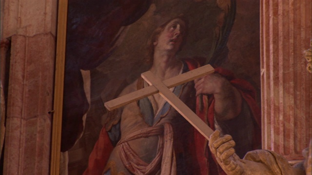 一尊雕像的手在一幅基督教画前举着一个基督教十字架。视频下载