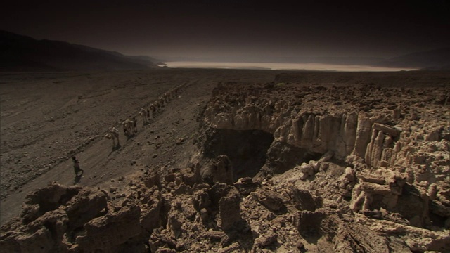 一列骆驼队在离开吉布提盐碱地后穿过沙漠。视频素材