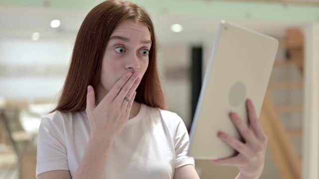 《红发年轻女性在平板电脑上面对失去的反应》视频素材