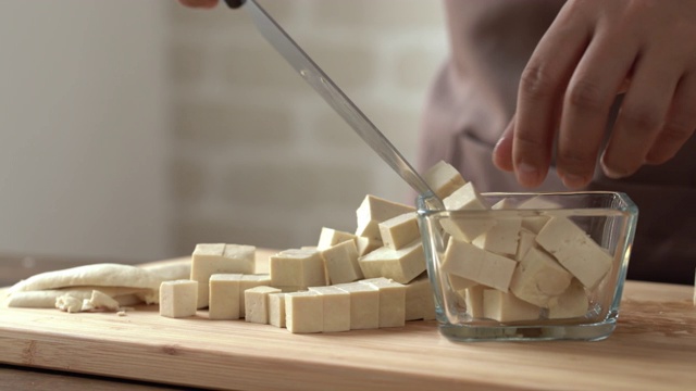 厨师将豆腐块放入切菜板上的玻璃碗中准备烹饪视频下载