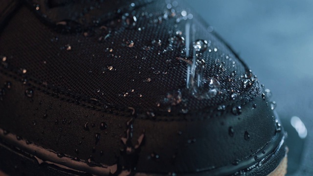 水滴在鞋面防水膜织物上，微距慢镜头拍摄。新防水技术的穿着和鞋类积极的生活方式视频素材