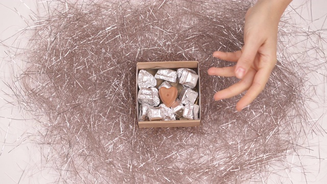 俯视图，一个女性的手打开礼物盒，并采取一个小美味的巧克力糖果。圣诞节的传统concept.mov视频下载